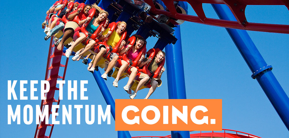 People riding a roller coaster at Worlds Of Fun - a tagline reads: Keep The Momentum Going